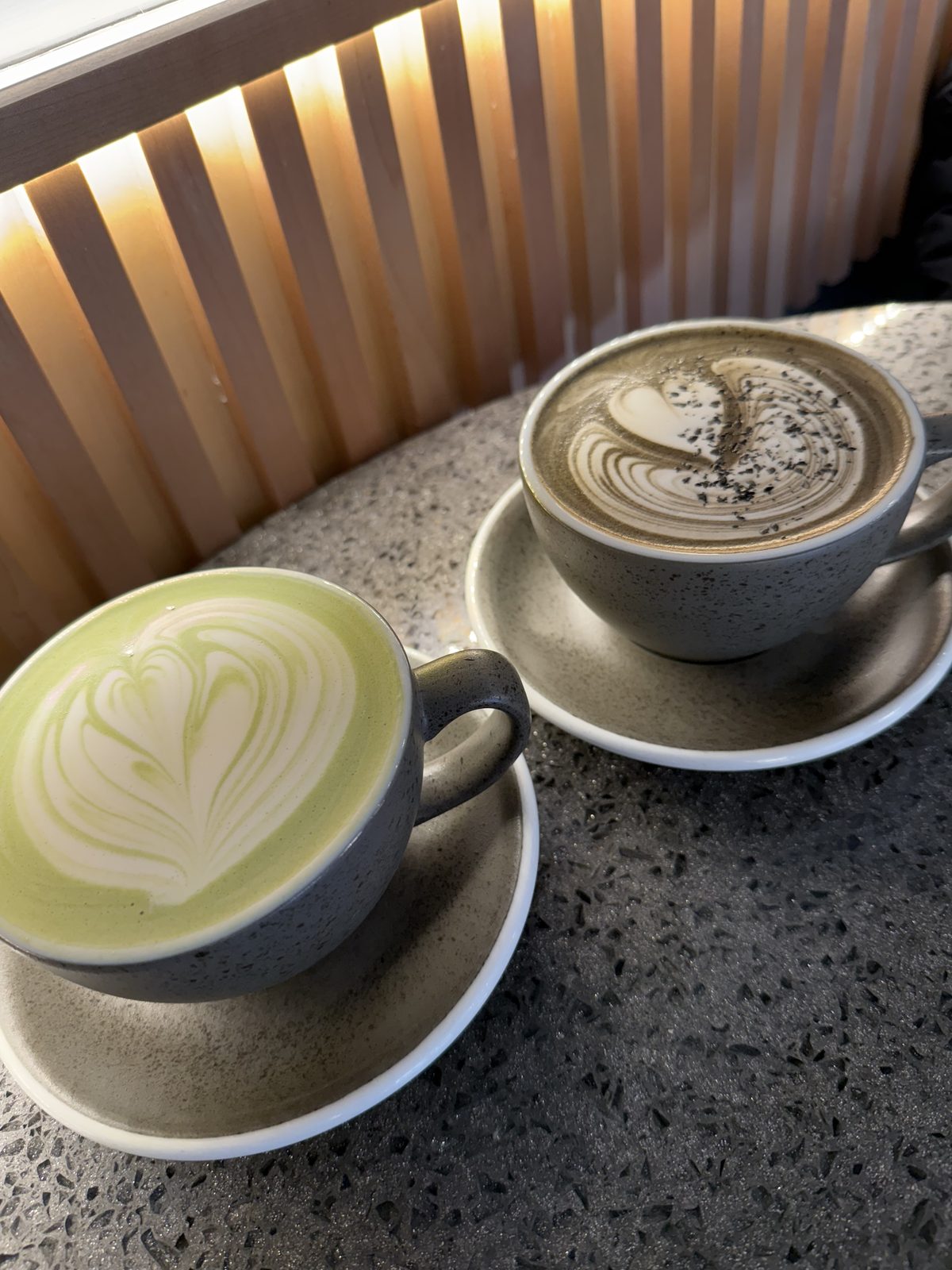Two lattes with latte art on a café counter